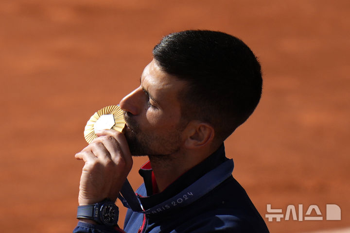 [파리=AP/뉴시스] 노바크 조코비치(2위·세르비아)가 4일(현지시각) 프랑스 파리의 스타드 롤랑가로스에서 열린 2024 파리올림픽 테니스 남자 단식 정상에 올라 금메달을 들고 입 맞추고 있다. 조코비치는 결승전에서 카를로스 알카라스(3위·스페인)를 2-0으로 꺾고 금메달을 따며 마침내 '골든 그랜드슬램'을 완성했다. 2024.08.05.